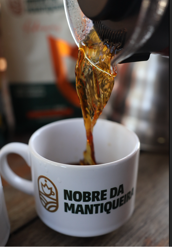 Café Adamas sendo servido em uma xícara Nobre da Mantiqueira, com a identidade da marca visível